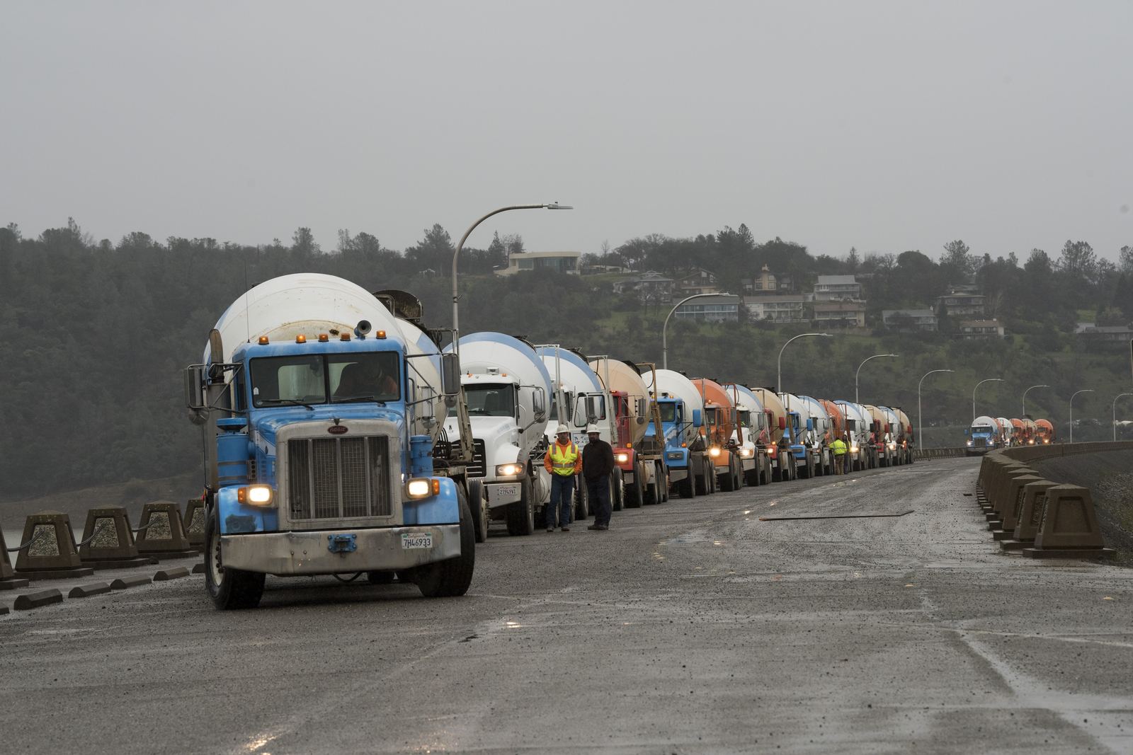 Concrete delivery trucks lined up at a dam and reservoir construction site